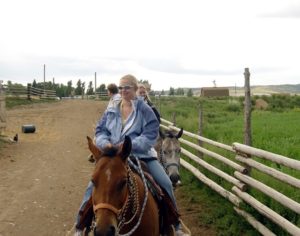 girl wearing sunglasses riding a horse