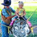 Little girl sitting on the bucking bull