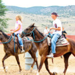 Family riding horses in the arena