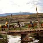 Family crossing a bridge while horseback ridding